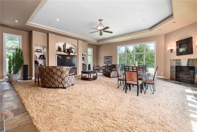 1709 Lake Alvamar Dr, Lawrence, KS 66047 - living area featuring a ceiling fan, a healthy amount of sunlight, a tray ceiling, and stone tile flooring