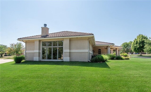 1709 Lake Alvamar Dr, Lawrence, KS 66047 - rear view of property with a chimney, stucco siding, a tile roof, and a lawn