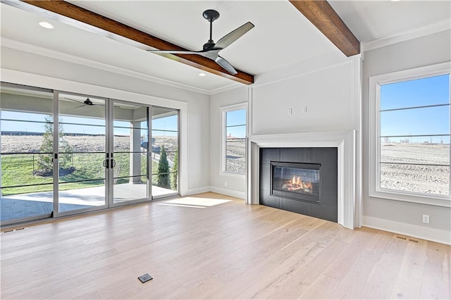 unfurnished living room with beamed ceiling, light hardwood / wood-style floors, ornamental molding, and a fireplace