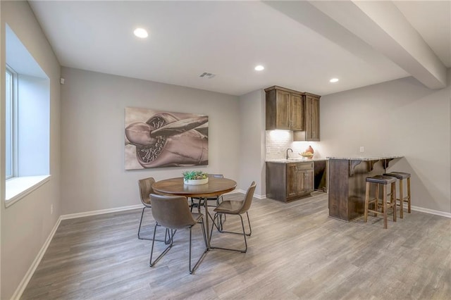 dining area with wood-type flooring, a healthy amount of sunlight, and wet bar