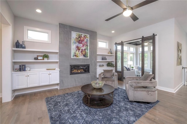 living room featuring dark hardwood / wood-style flooring, ceiling fan, a tile fireplace, and built in shelves