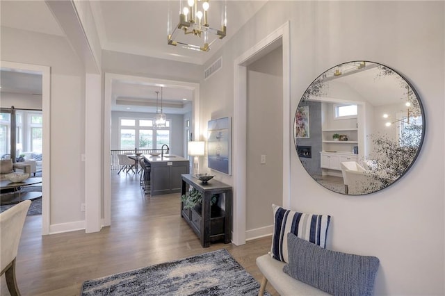 12200 W 138th Pl, Overland Park, KS 66221 - hallway with a chandelier, wood finished floors, a sink, and baseboards