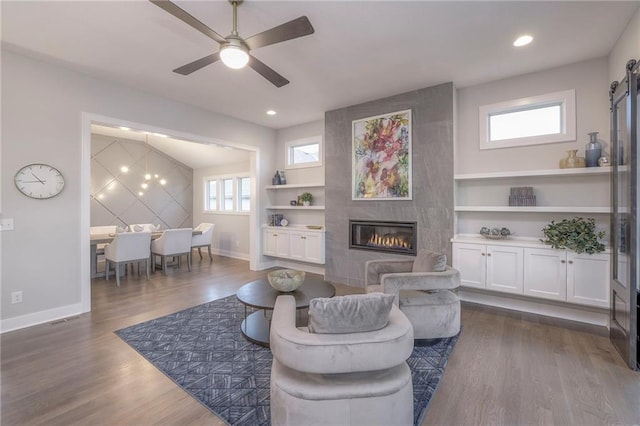 12200 W 138th Pl, Overland Park, KS 66221 - living area with a fireplace, baseboards, dark wood-type flooring, built in shelves, and a ceiling fan