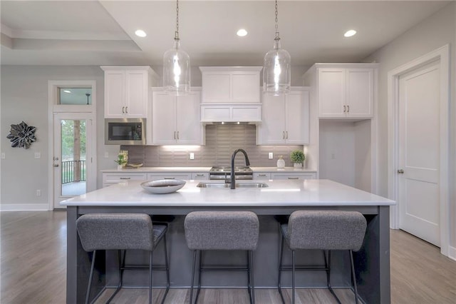12200 W 138th Pl, Overland Park, KS 66221 - kitchen with stainless steel microwave, a sink, decorative backsplash, white cabinetry, and recessed lighting