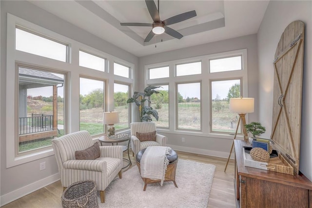 sunroom featuring ceiling fan and a raised ceiling