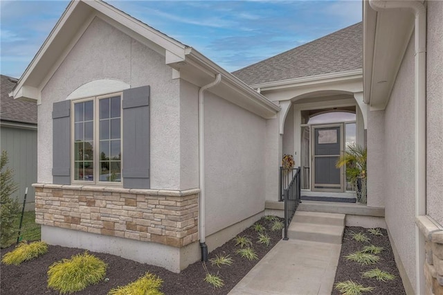 13812 Quigley St, Overland Park, KS 66221 - doorway to property featuring stucco siding, stone siding, and roof with shingles