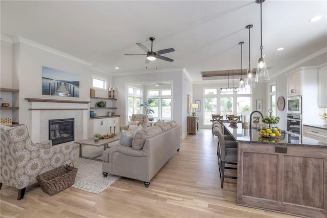 13812 Quigley St, Overland Park, KS 66221 - living room with ceiling fan, light wood finished floors, crown molding, recessed lighting, and a tile fireplace
