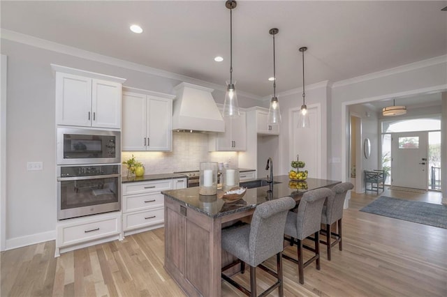 13812 Quigley St, Overland Park, KS 66221 - kitchen featuring stainless steel appliances, premium range hood, a kitchen breakfast bar, white cabinets, and tasteful backsplash