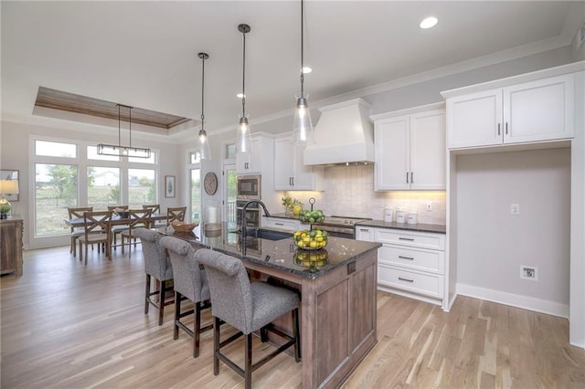 13812 Quigley St, Overland Park, KS 66221 - kitchen featuring a sink, custom range hood, ornamental molding, appliances with stainless steel finishes, and a breakfast bar