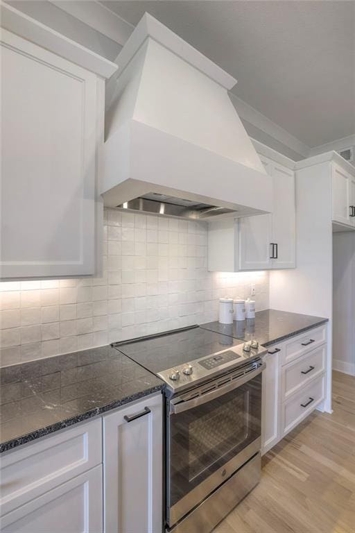 13812 Quigley St, Overland Park, KS 66221 - kitchen with electric range, custom exhaust hood, white cabinets, dark stone counters, and decorative backsplash