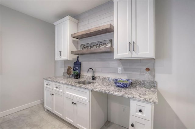 13812 Quigley St, Overland Park, KS 66221 - kitchen with a sink, decorative backsplash, white cabinets, baseboards, and light stone countertops