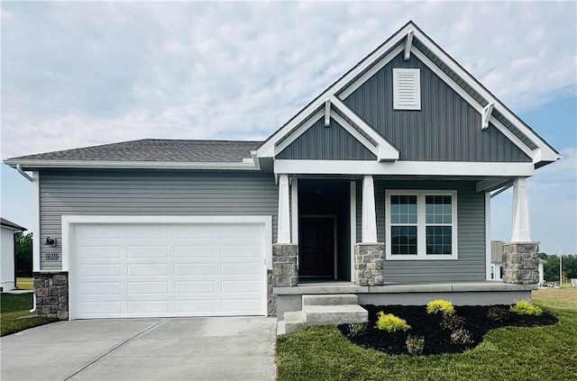 craftsman-style house featuring a garage, driveway, covered porch, and stone siding