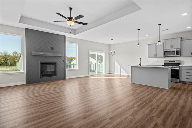 kitchen with open floor plan, stainless steel appliances, a kitchen island with sink, and gray cabinetry