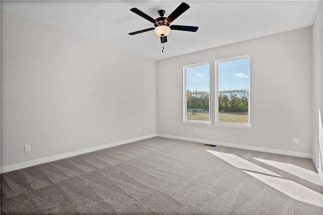 carpeted spare room featuring a ceiling fan, visible vents, and baseboards