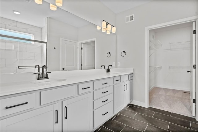 full bathroom with double vanity, baseboards, visible vents, and a sink