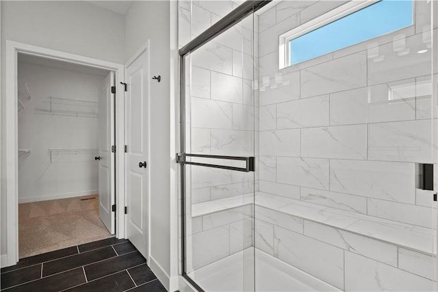 full bath featuring a stall shower, a walk in closet, and baseboards