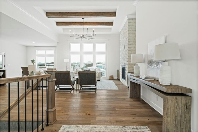 interior space featuring dark wood-type flooring, a brick fireplace, a chandelier, and beamed ceiling