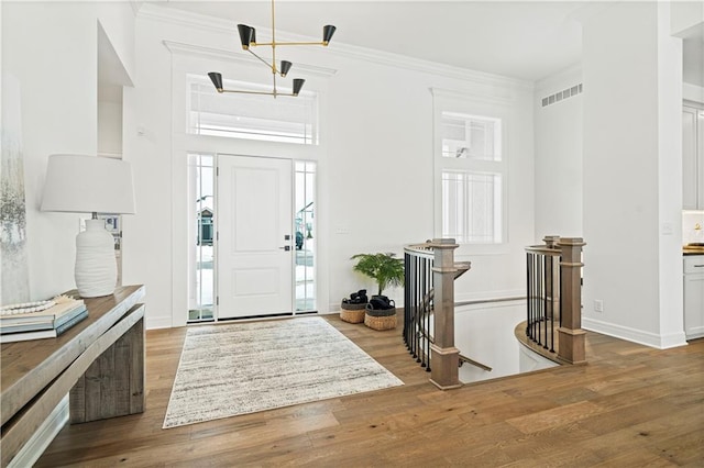 entrance foyer with crown molding, a notable chandelier, and wood-type flooring