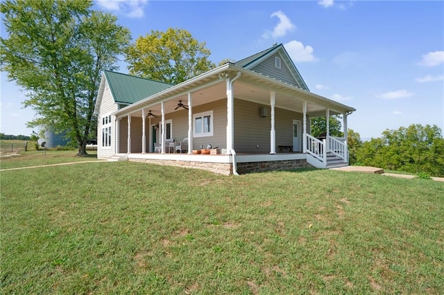 rear view of house featuring ceiling fan, covered porch, and a lawn