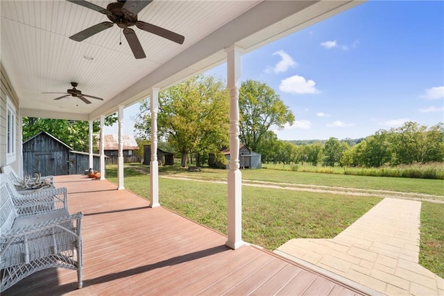 wooden deck with ceiling fan, a yard, and an outdoor structure