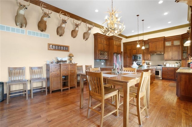 dining space featuring crown molding, an inviting chandelier, light hardwood / wood-style floors, and sink