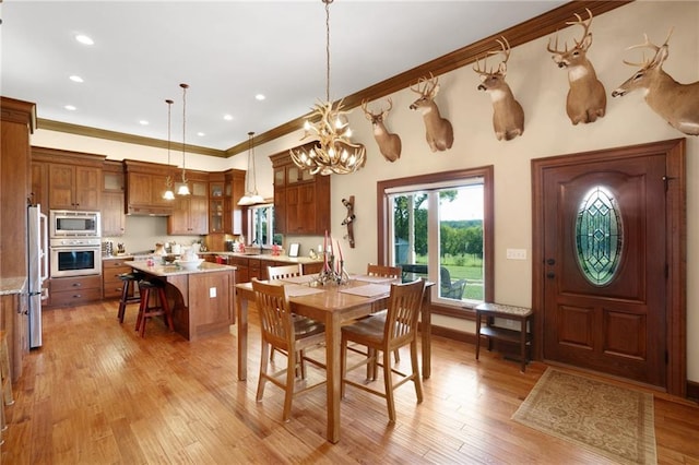 dining room featuring light hardwood / wood-style flooring, a notable chandelier, and ornamental molding