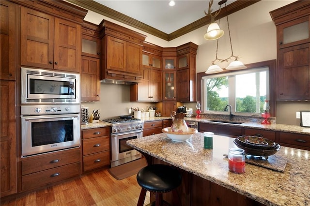 kitchen featuring light stone countertops, a kitchen bar, sink, light hardwood / wood-style flooring, and stainless steel appliances