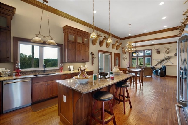 kitchen featuring a kitchen breakfast bar, sink, light wood-type flooring, a center island, and dishwasher