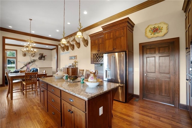 kitchen with high end refrigerator, hanging light fixtures, dark hardwood / wood-style flooring, light stone countertops, and an inviting chandelier