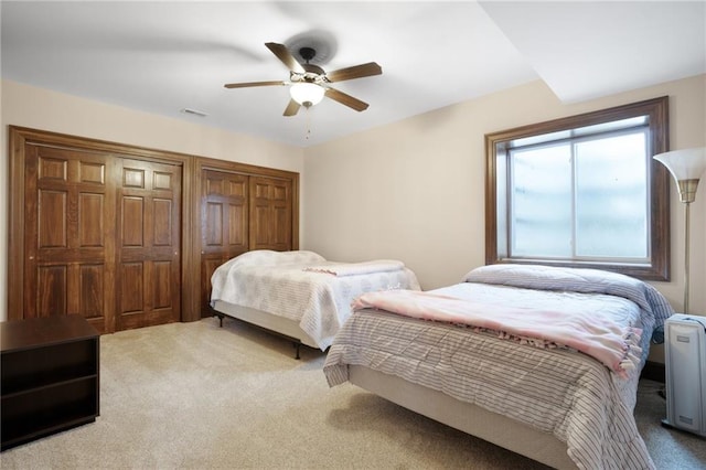 carpeted bedroom with multiple closets and ceiling fan