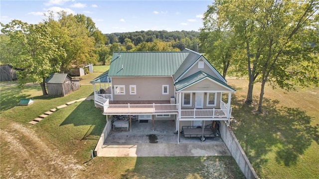 back of property with a wooden deck, a lawn, a patio area, and a shed