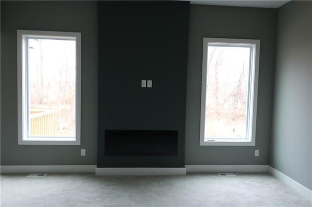 unfurnished living room featuring a fireplace, plenty of natural light, and light colored carpet