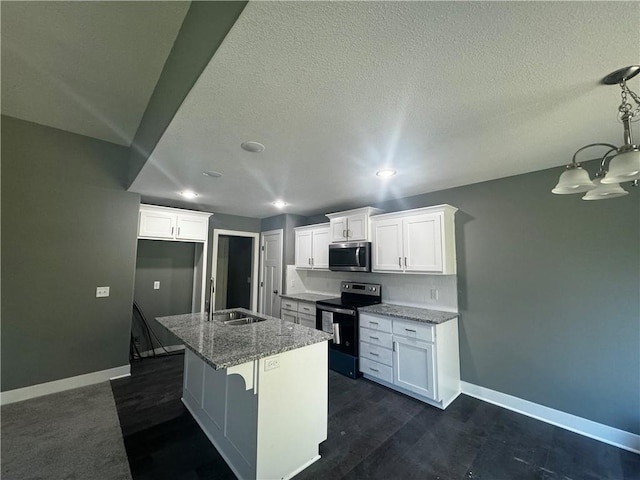 kitchen featuring white cabinetry, sink, stainless steel appliances, light stone counters, and a kitchen island with sink