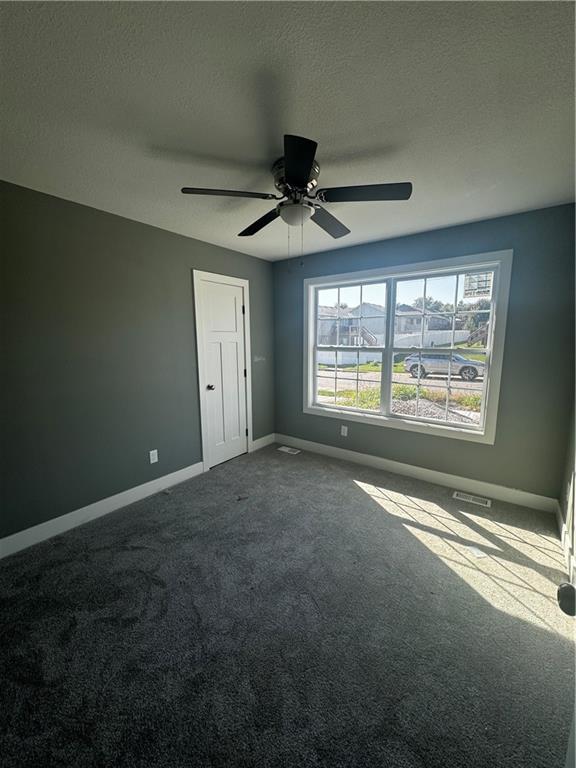 carpeted empty room with a textured ceiling and ceiling fan