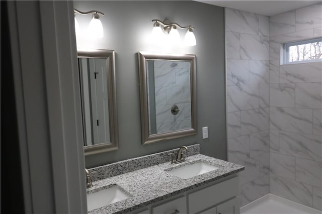 bathroom with a tile shower and vanity