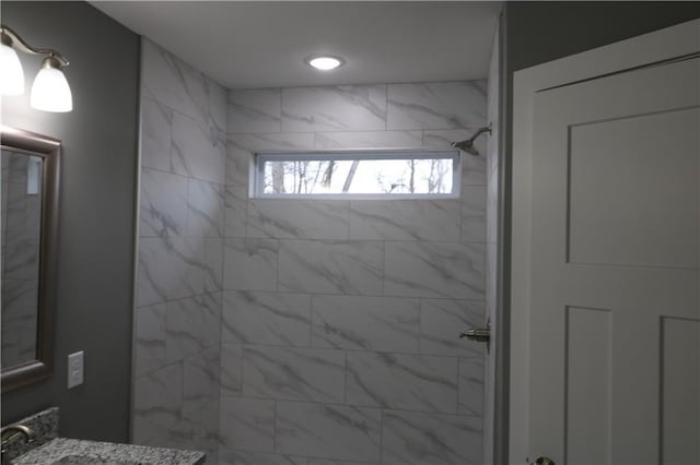 bathroom with a tile shower and vanity