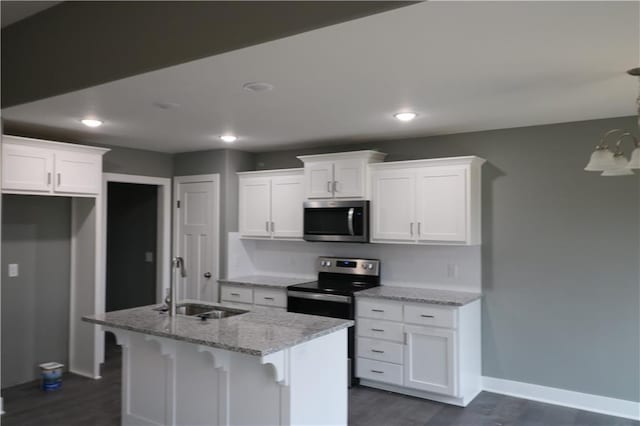 kitchen featuring light stone counters, stainless steel appliances, sink, white cabinetry, and an island with sink