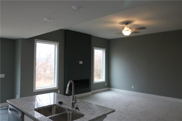 kitchen featuring carpet flooring, ceiling fan, sink, light stone counters, and stainless steel dishwasher