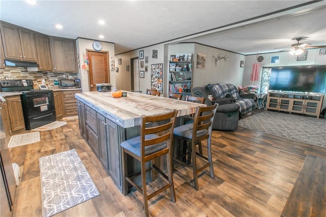 kitchen with a center island, a kitchen bar, ceiling fan, wood-type flooring, and black electric range