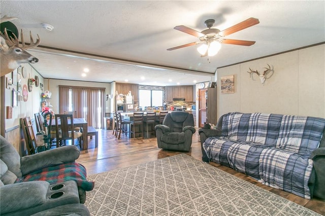 living room with a textured ceiling, ceiling fan, and hardwood / wood-style flooring