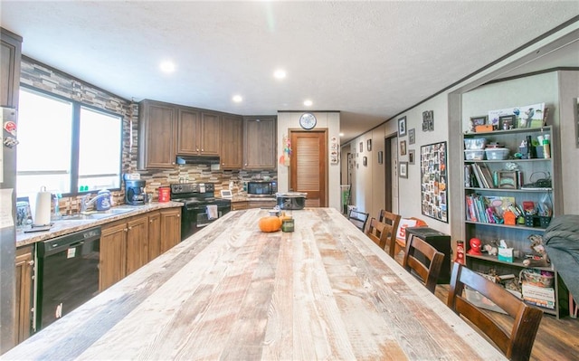 kitchen with wood counters, hardwood / wood-style flooring, tasteful backsplash, black appliances, and sink