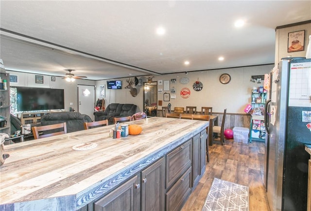 kitchen with ceiling fan, stainless steel refrigerator, wood counters, dark brown cabinetry, and dark hardwood / wood-style flooring