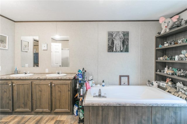 bathroom with a tub, hardwood / wood-style floors, ornamental molding, and dual vanity