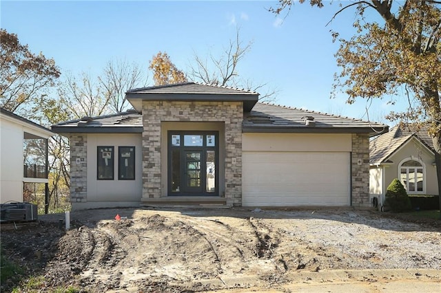 prairie-style home with central AC unit and a garage