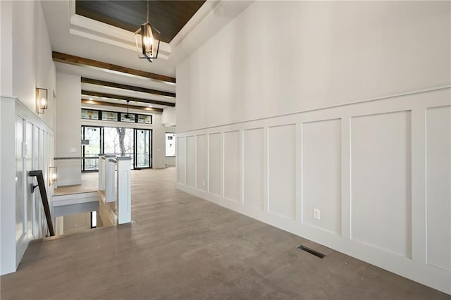 111 Teton Rdg, Lake Winnebago, MO 64034 - hallway featuring a decorative wall, an upstairs landing, a towering ceiling, a tray ceiling, and a chandelier