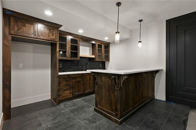 kitchen featuring pendant lighting, kitchen peninsula, decorative backsplash, and dark brown cabinets