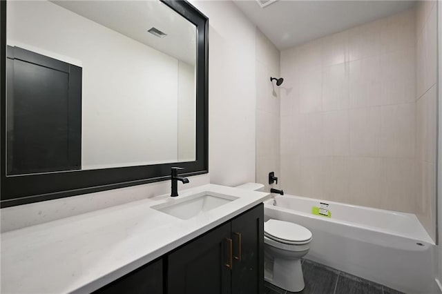 full bathroom with tile patterned floors, vanity, tiled shower / bath combo, and toilet