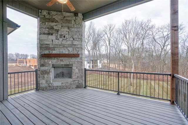 deck with ceiling fan and an outdoor stone fireplace