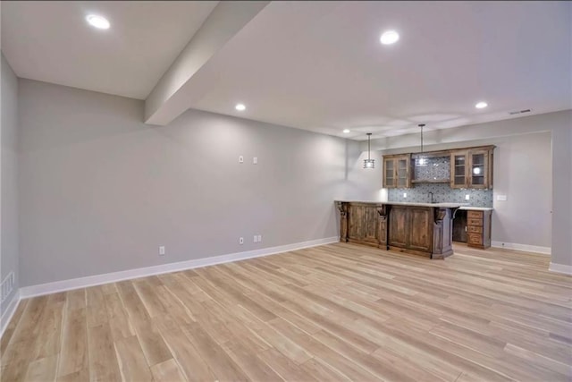 bar featuring decorative backsplash, sink, decorative light fixtures, and light hardwood / wood-style flooring