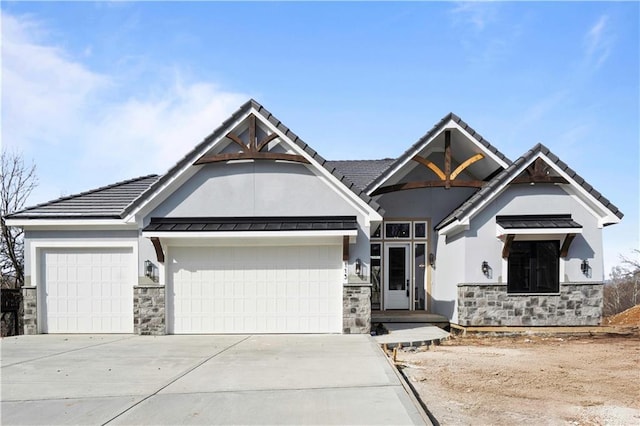 view of front of property with metal roof, an attached garage, concrete driveway, stone siding, and a standing seam roof